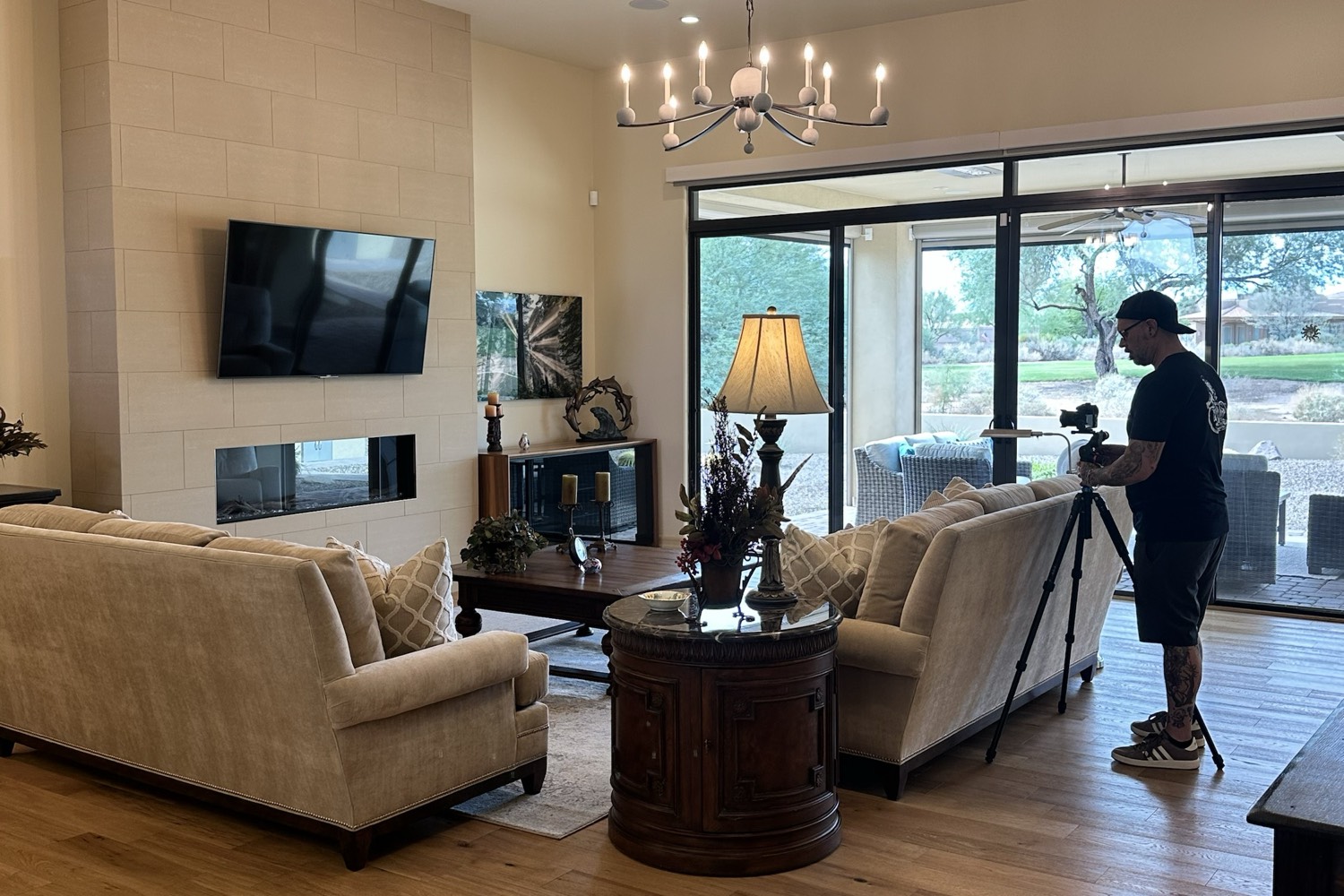 Professional photographer setting up a camera on a tripod in an Arizona great room with sofas, a fireplace and glass doors to the patio