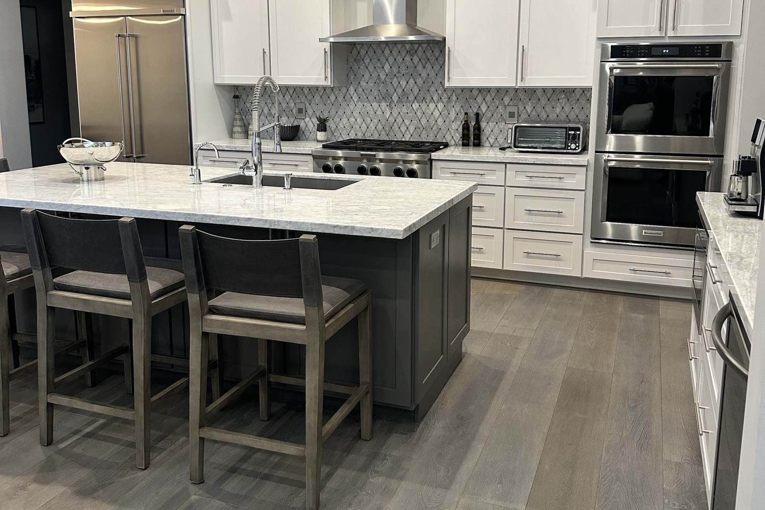 Updated Arizona kitchen with white cabinets, a gray island with a marble-look countertop, stainless steel appliances and wood floors